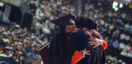 毕业典礼上，身穿学士服的毕业生与身穿长袍的教员衷心拥抱